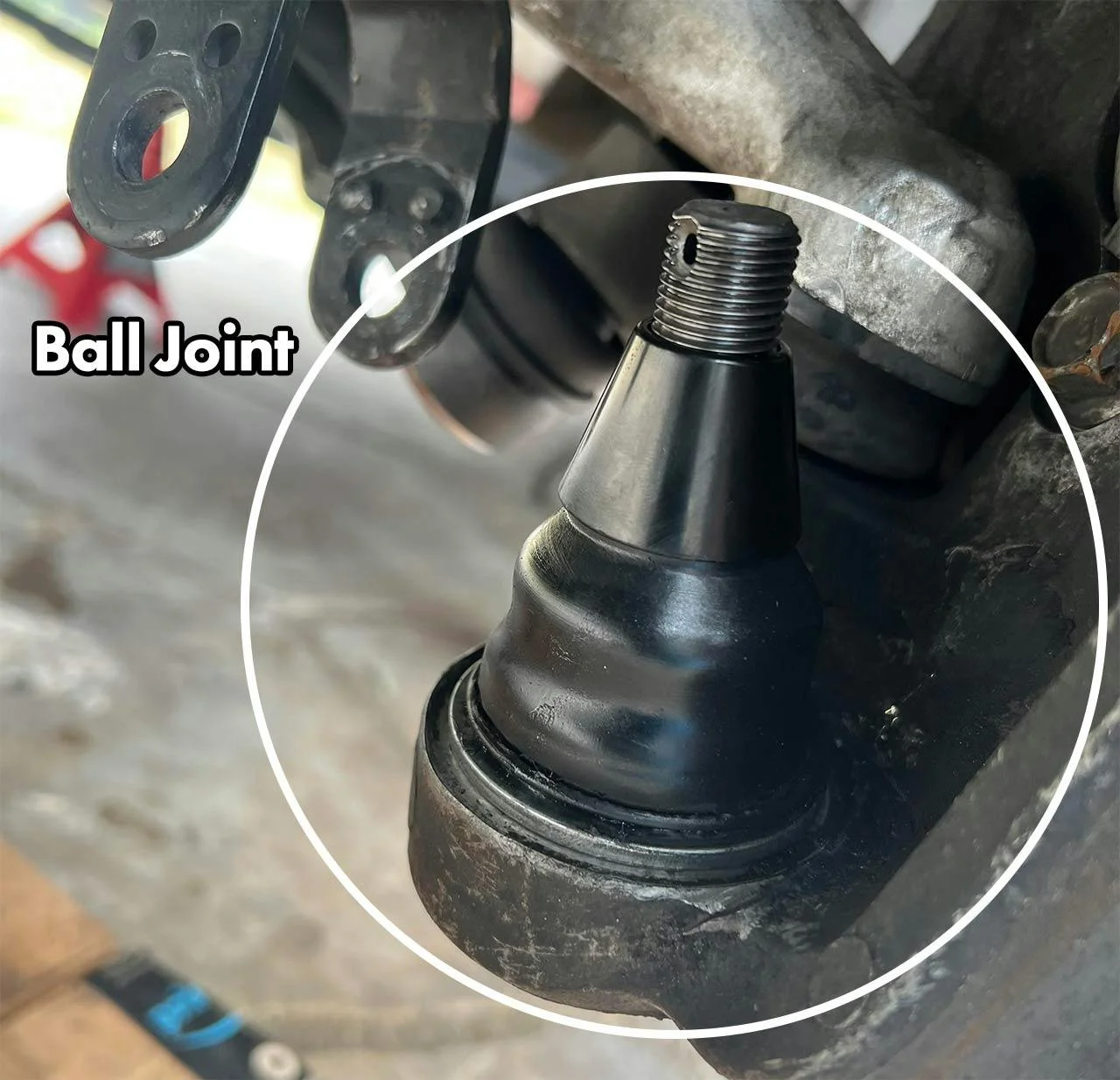 Close-up of a black ball joint component on truck suspension with threaded stud visible