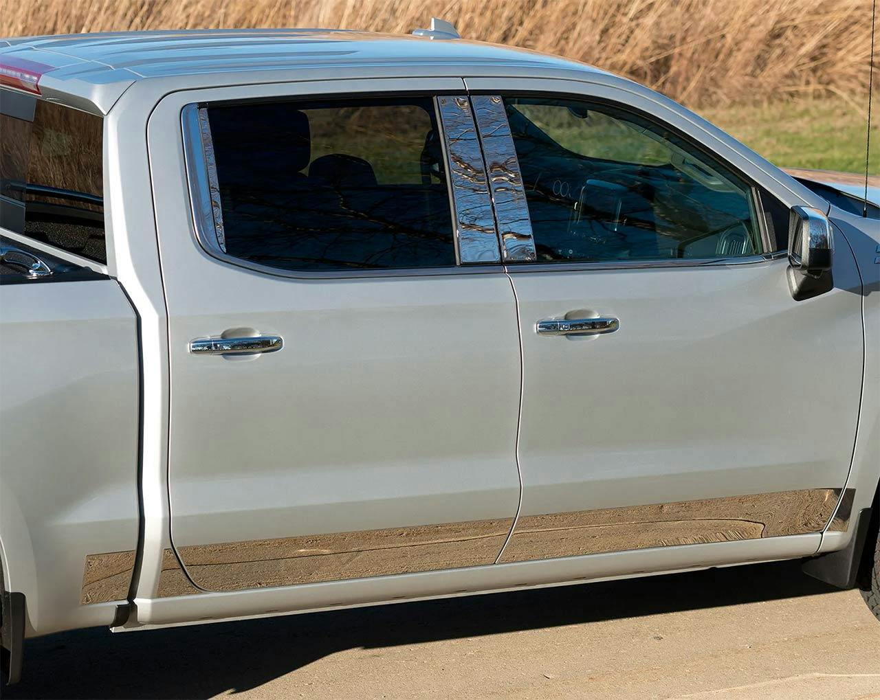 White pickup truck with wood-grain door panels and chrome window trim parked on gravel.