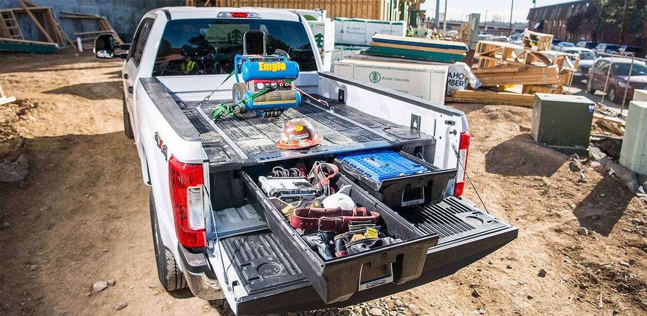 White pickup truck with sliding drawer system open in bed, displaying tools, toolbox, and equipment neatly organized in