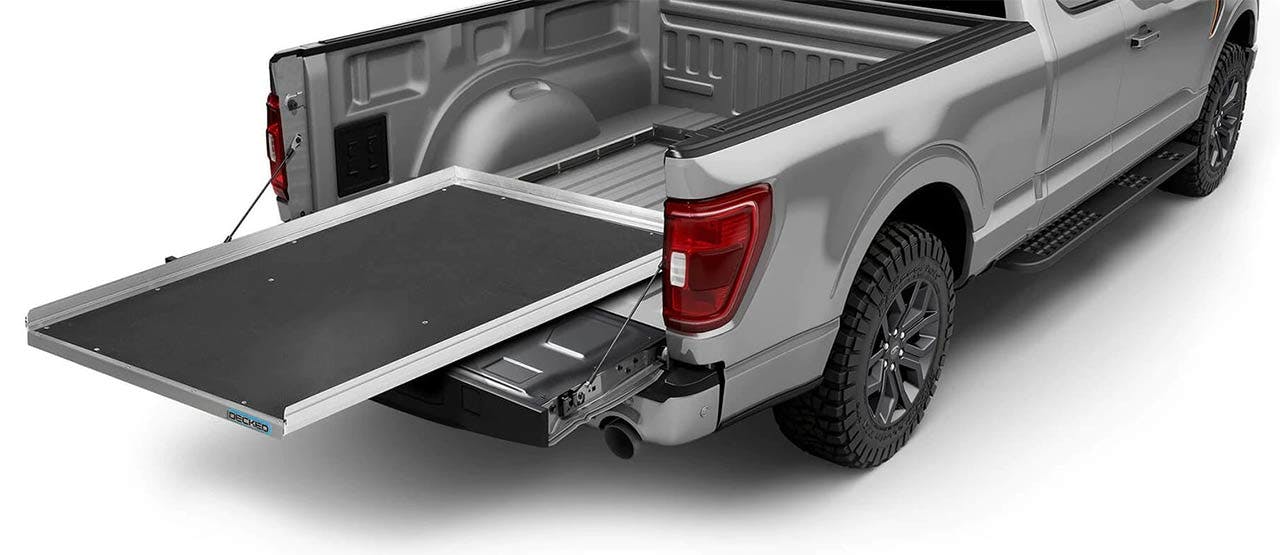 Silver pickup truck with black sliding cargo tray extended from the bed and tool storage drawer partially pulled out