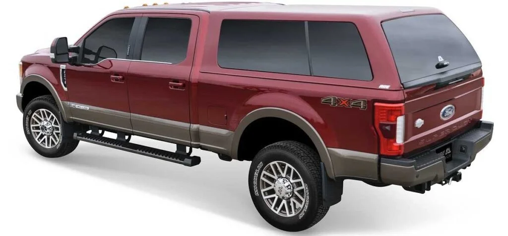 Red and brown Ford Super Duty truck with black running boards and hard tonneau cover on bed