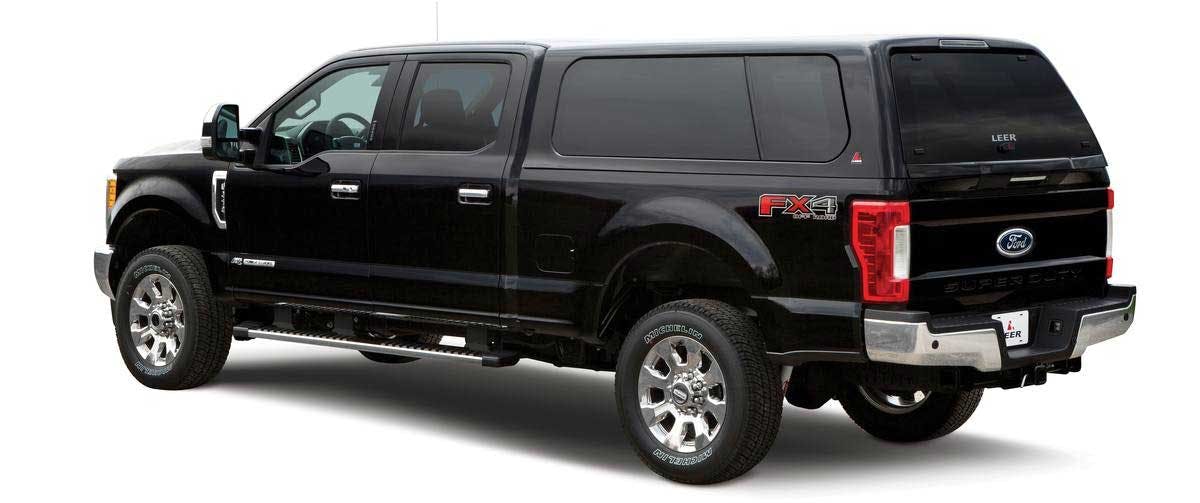 Black Ford F-250 Super Duty pickup truck with LEER camper shell and tinted rear windows, shown from side angle.