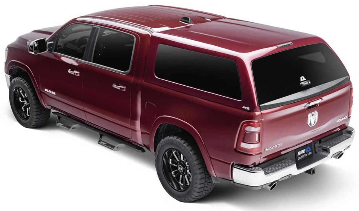 Burgundy Ram pickup truck with a paint-matched camper shell on the bed, viewed from the rear three-quarter angle.