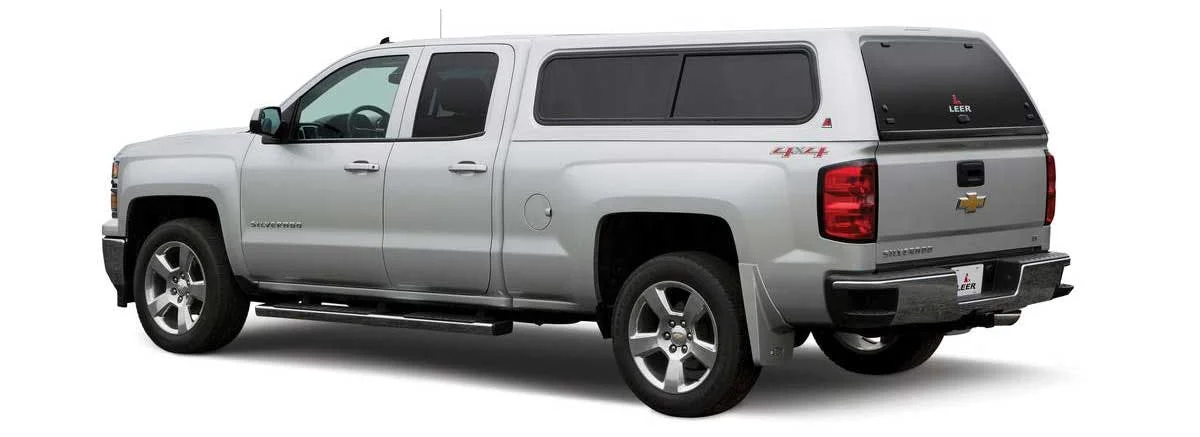 Silver Chevrolet Silverado with black mid-height truck bed canopy featuring tinted windows and roof rails.