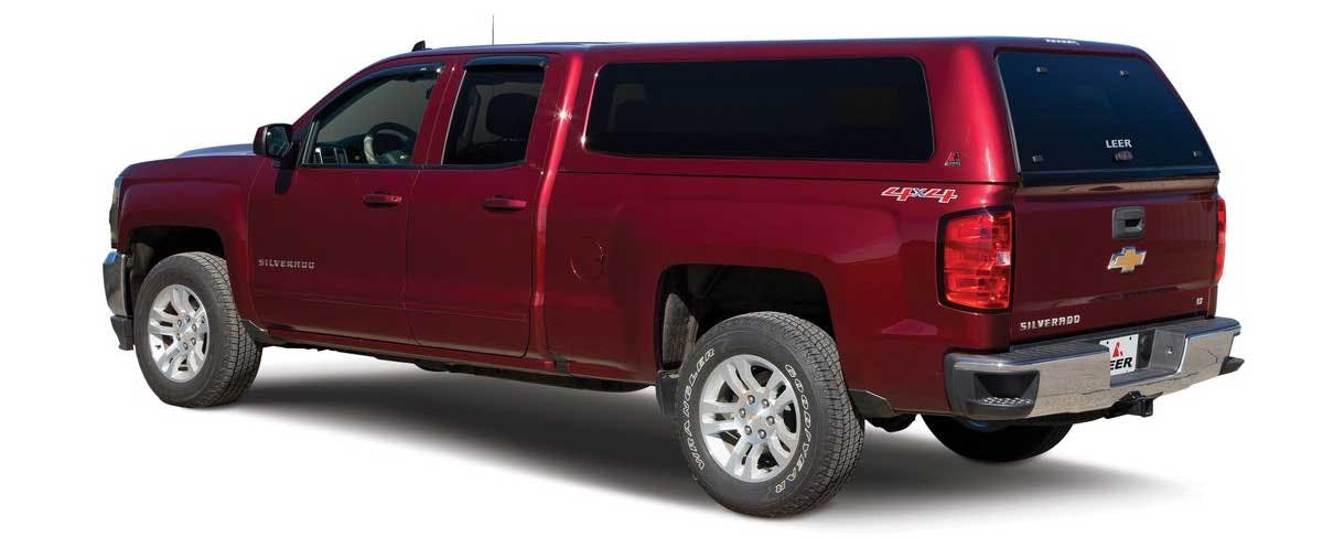 Maroon Chevrolet Silverado crew cab pickup truck with four doors, viewed from the side and rear at an angle against a white