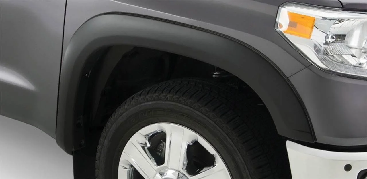 Gray pickup truck wheel well with black tire, white alloy wheel, and gray fender flare visible along the side