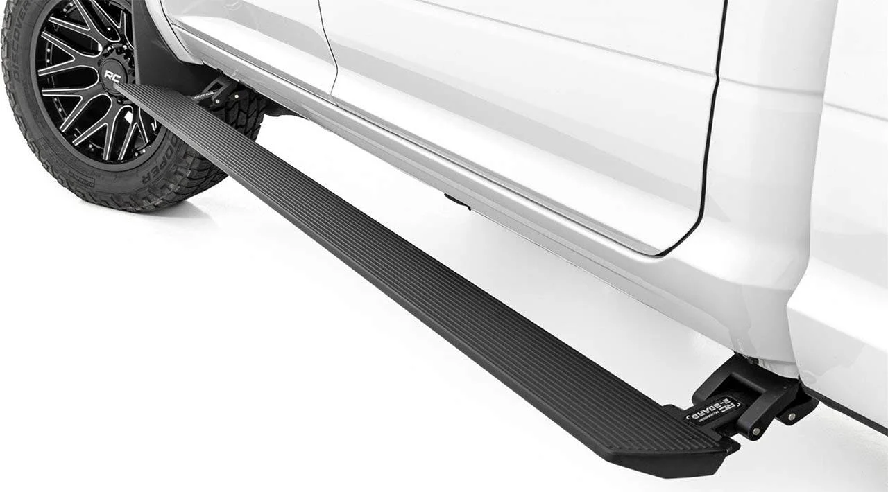 Black textured running board mounted flush against white truck's side, with tire and wheel visible behind it