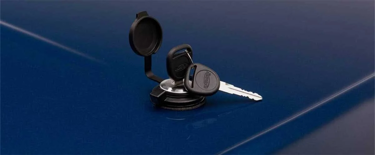 Black push-button latch with key and circular cover attached to blue truck bed surface