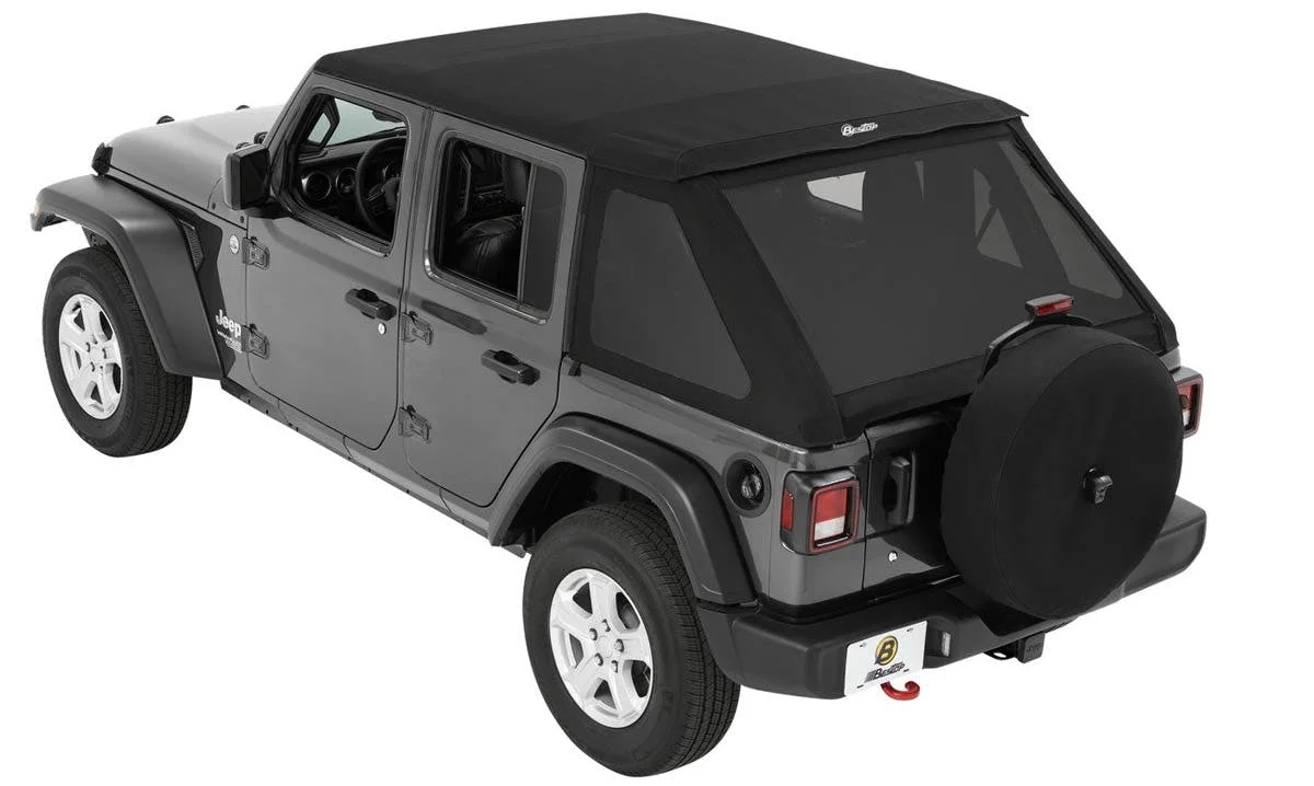 Gray Jeep Wrangler four-door with black soft top and spare tire cover on rear bumper