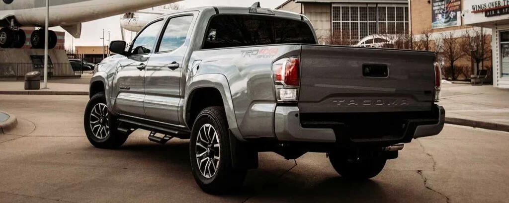 Silver Toyota Tacoma truck parked in a lot with black nerf bars running along both sides below the doors.