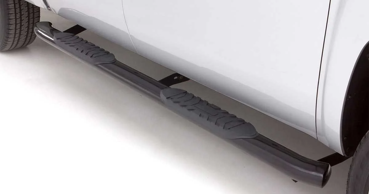 Black textured nerf bar running along the side of a white pickup truck with step platform and drainage vents.