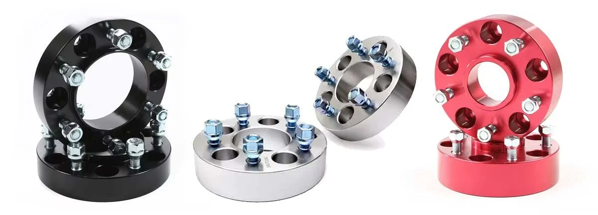 Black, silver, and red wheel spacers with multiple bolt holes and studs arranged in a row