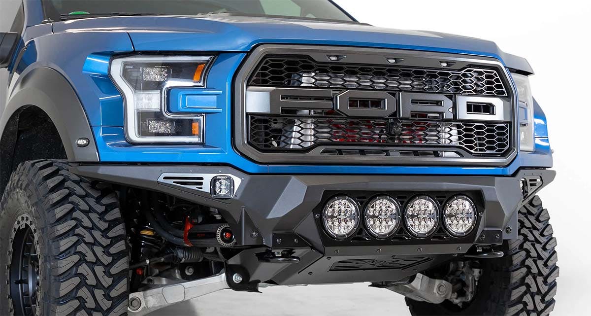 Blue pickup truck front end with black bumper, four round LED lights, and large all-terrain tires