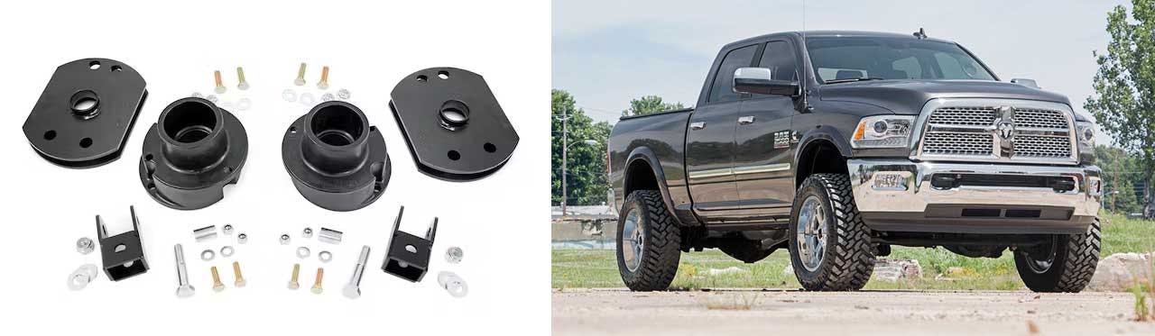 Suspension lift kit components including spacers, brackets, and hardware displayed next to lifted Dodge Ram truck on pavement