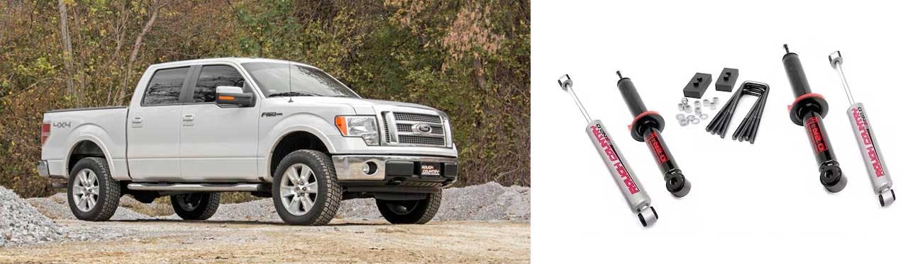 White pickup truck on gravel next to collection of shock absorbers and lift kit suspension components.