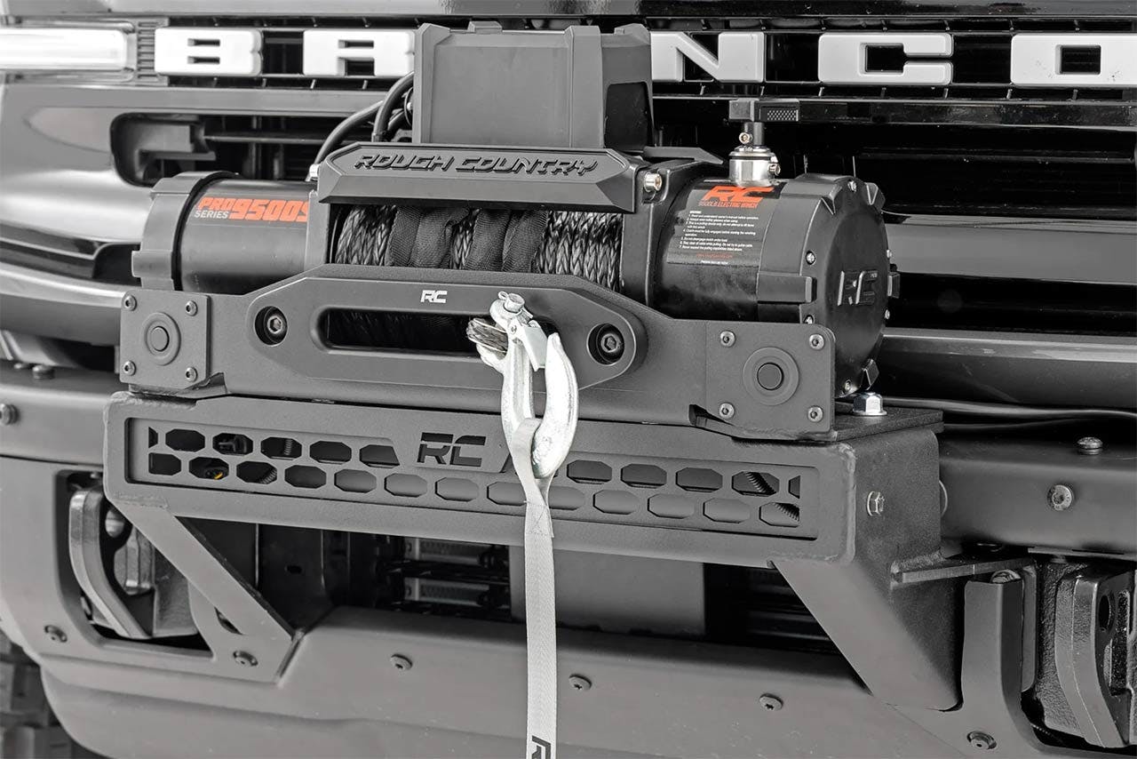 Rough Country winch mounted on truck bumper with gray synthetic rope attached to chrome clevis hook