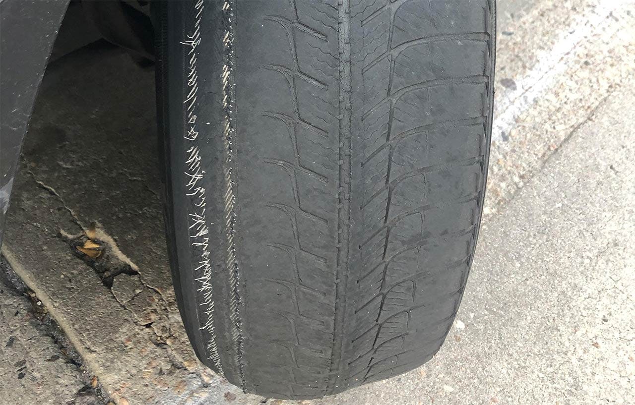 Close-up of a truck tire tread on pavement, showing wear patterns and grooves in the black rubber.