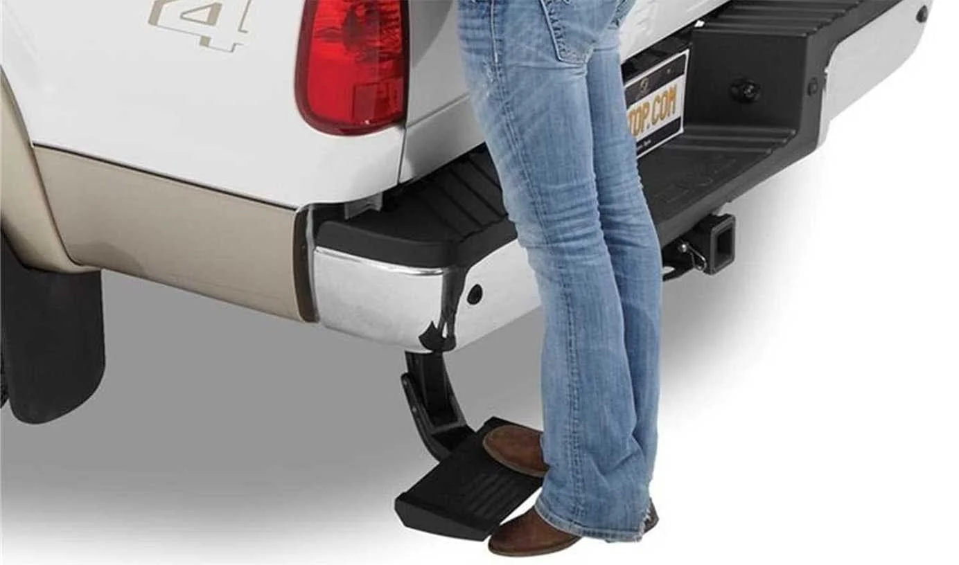 Person stepping onto a black power running board extending from the side of a white pickup truck