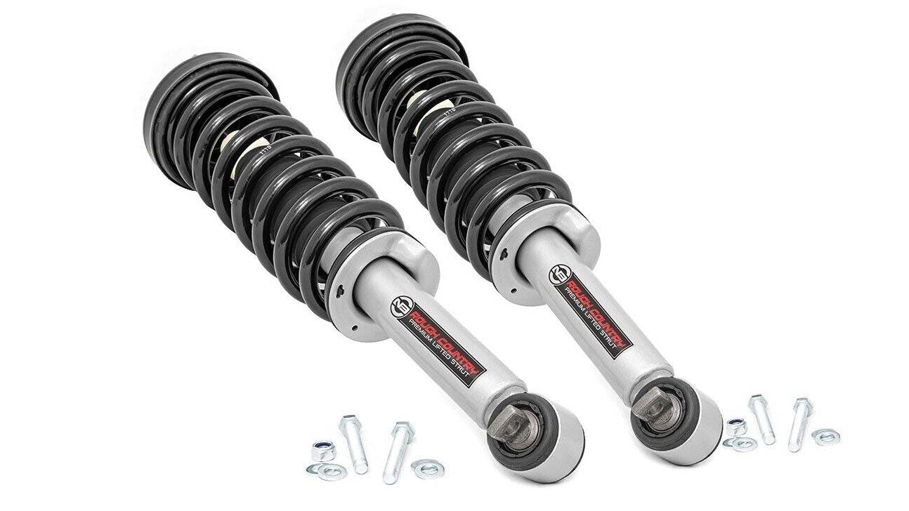 Pair of silver and black coil-over struts with preloaded springs displayed with mounting hardware