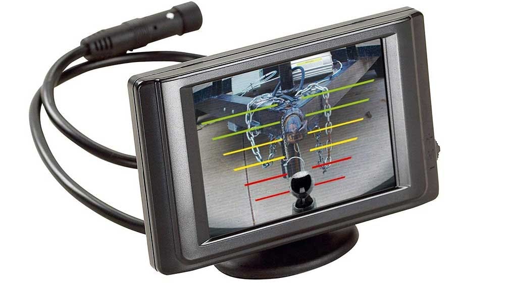 Backup camera monitor displaying truck hitch ball and chains with colored guide lines for reversing alignment.