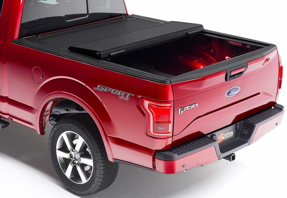 Red Ford F150 truck with black tonneau cover partially open over the truck bed