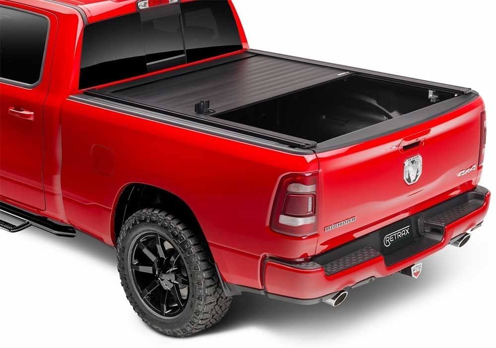 Red pickup truck with black retractable tonneau cover partially rolled open over the bed