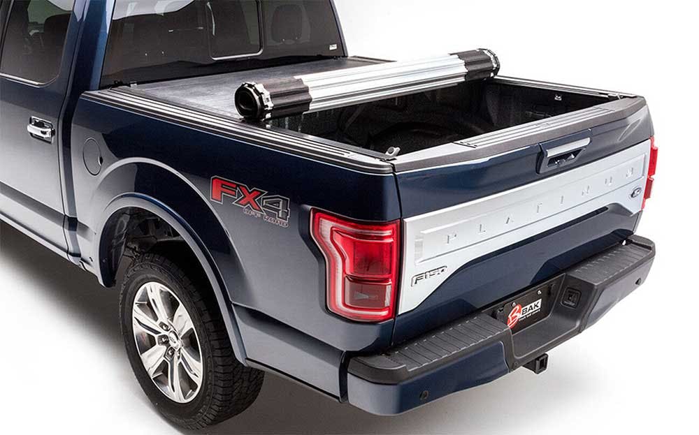 Retractable truck bed cover rolled up on a blue and silver pickup truck bed