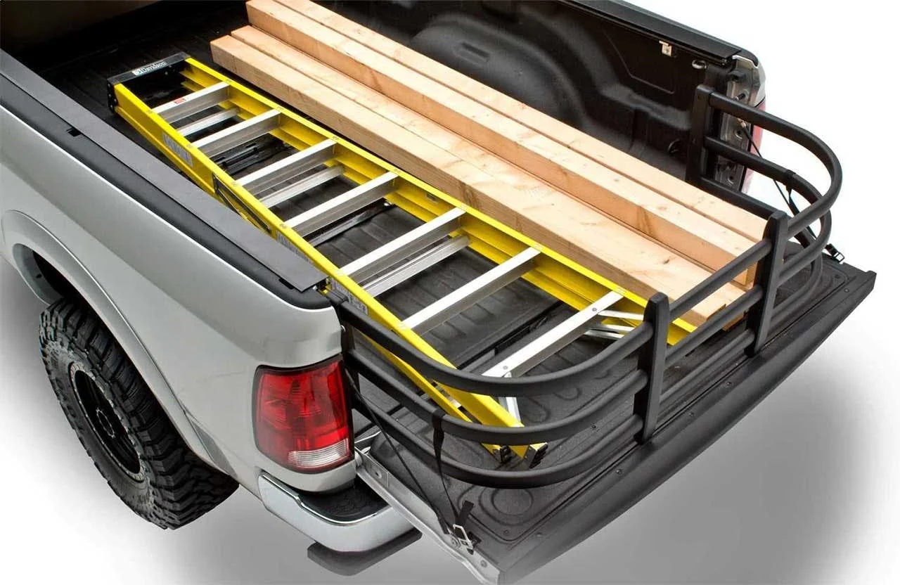 Yellow truck bed extender with aluminum rungs holding lumber and wooden planks in white pickup truck bed
