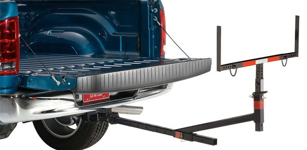 Blue pickup truck with open tailgate and metal gate-style bed extender deployed horizontally behind it
