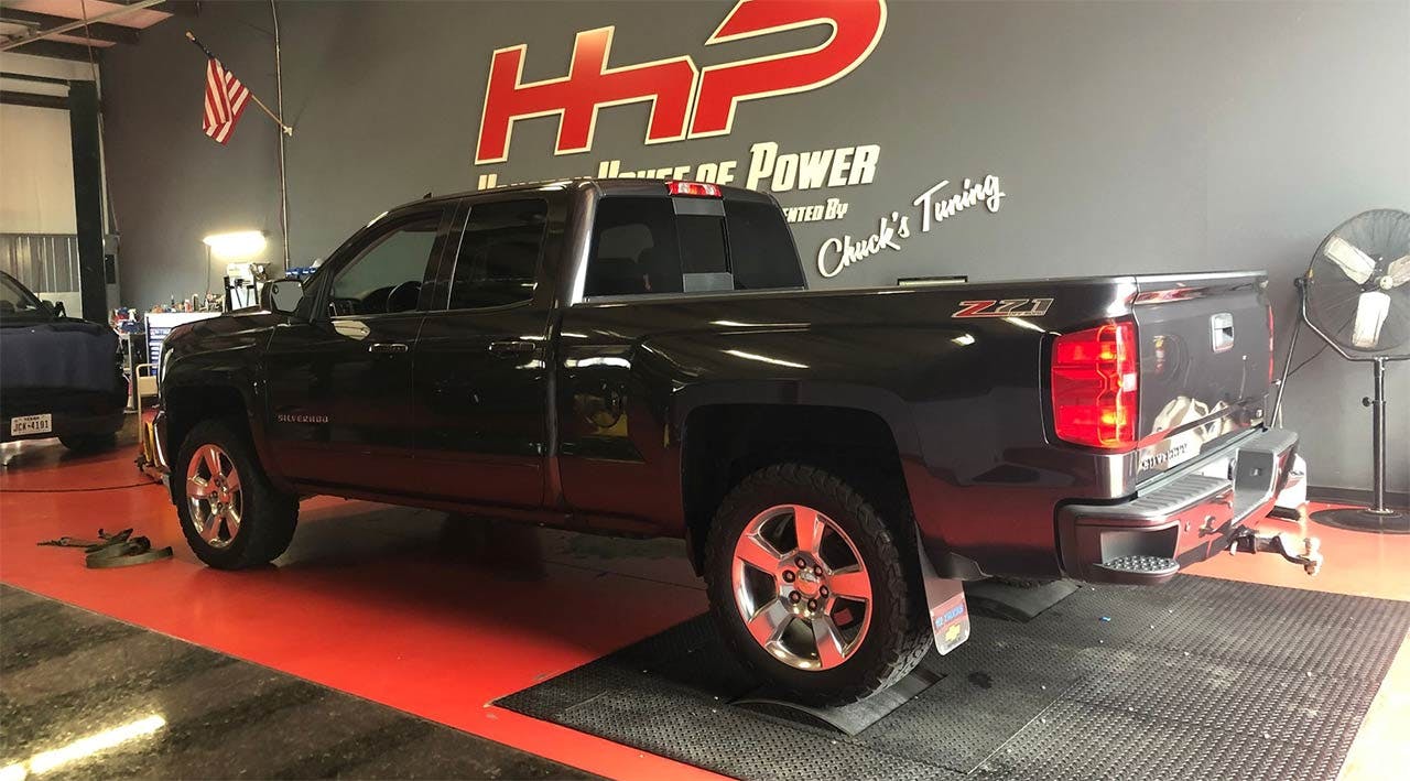 Black pickup truck on red display platform inside a showroom with HHP branding on wall behind it.