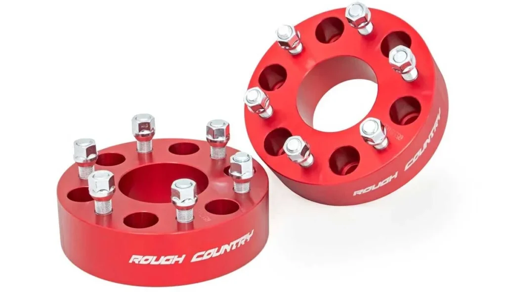 Two red aluminum wheel spacers with stud holes and chrome lug nuts, displaying "Rough Country" branding on the side