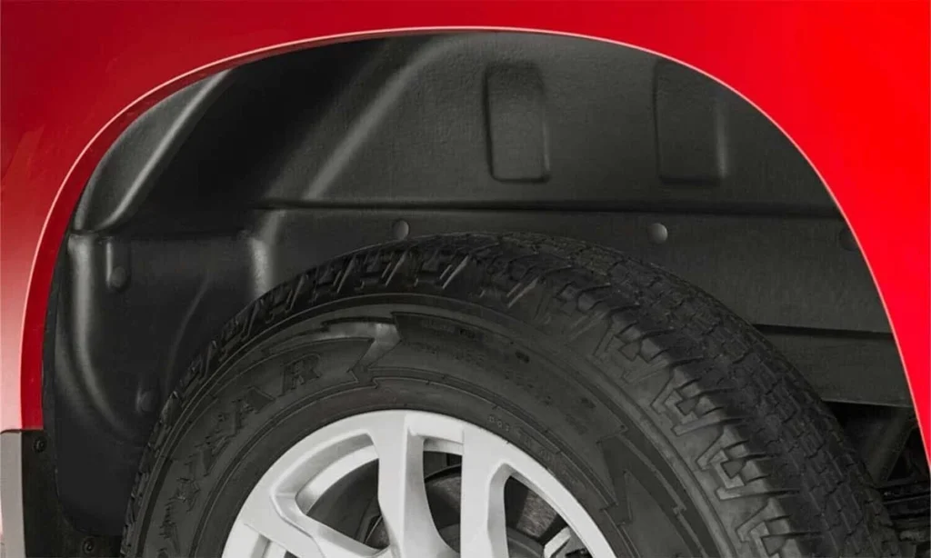 Black truck wheel well liner installed behind white alloy wheel against red vehicle body