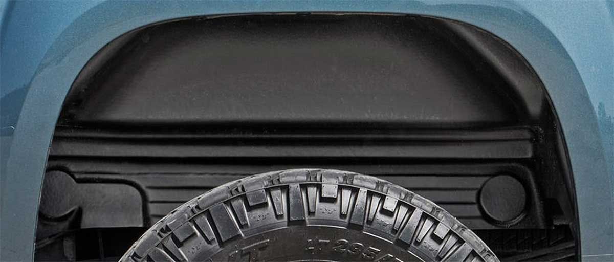 Black polyethylene wheel well liner installed inside a truck's wheel opening, covering the frame rail and inner fender.