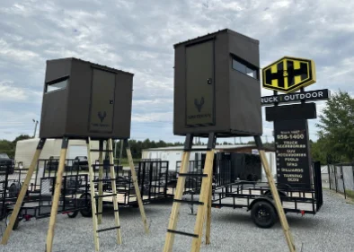 Two elevated shooting houses on tower stands outside an H&H Truck & Outdoor store