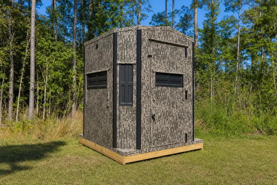 Shadow Hunter 6x6 Octagon blind sitting at ground level on a mowed strip beside a pine woodlot