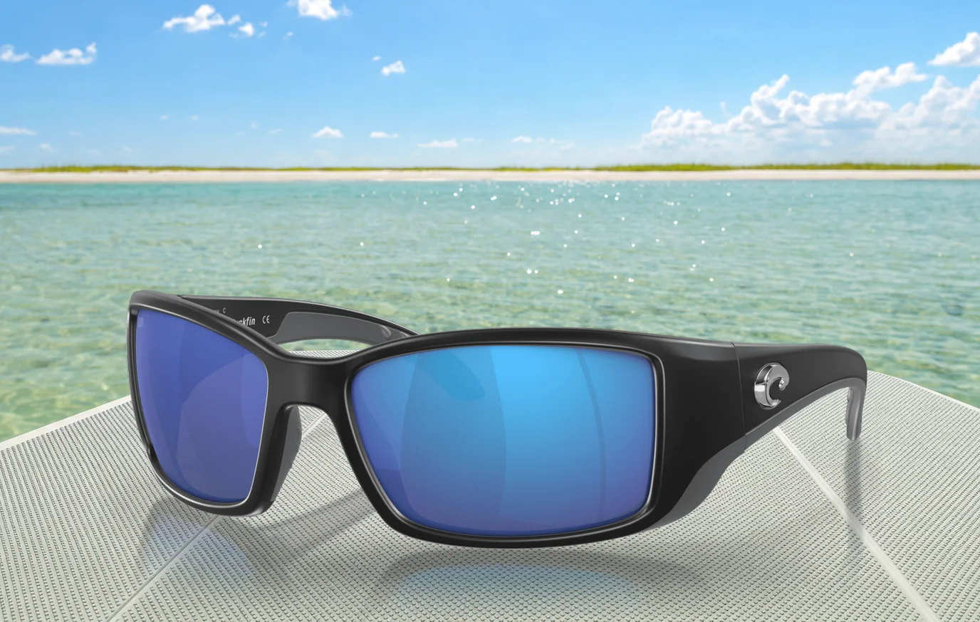 Costa Del Mar Blackfin sunglasses with blue mirror 580G lenses, on a boat deck over a shallow saltwater flat